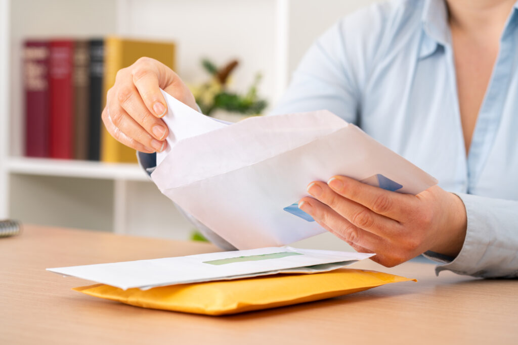Close up of woman hands putting a letter inside an envelope on a