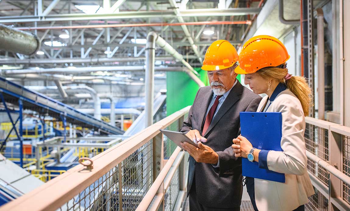 man-woman-in-factory-looking-at-tablet